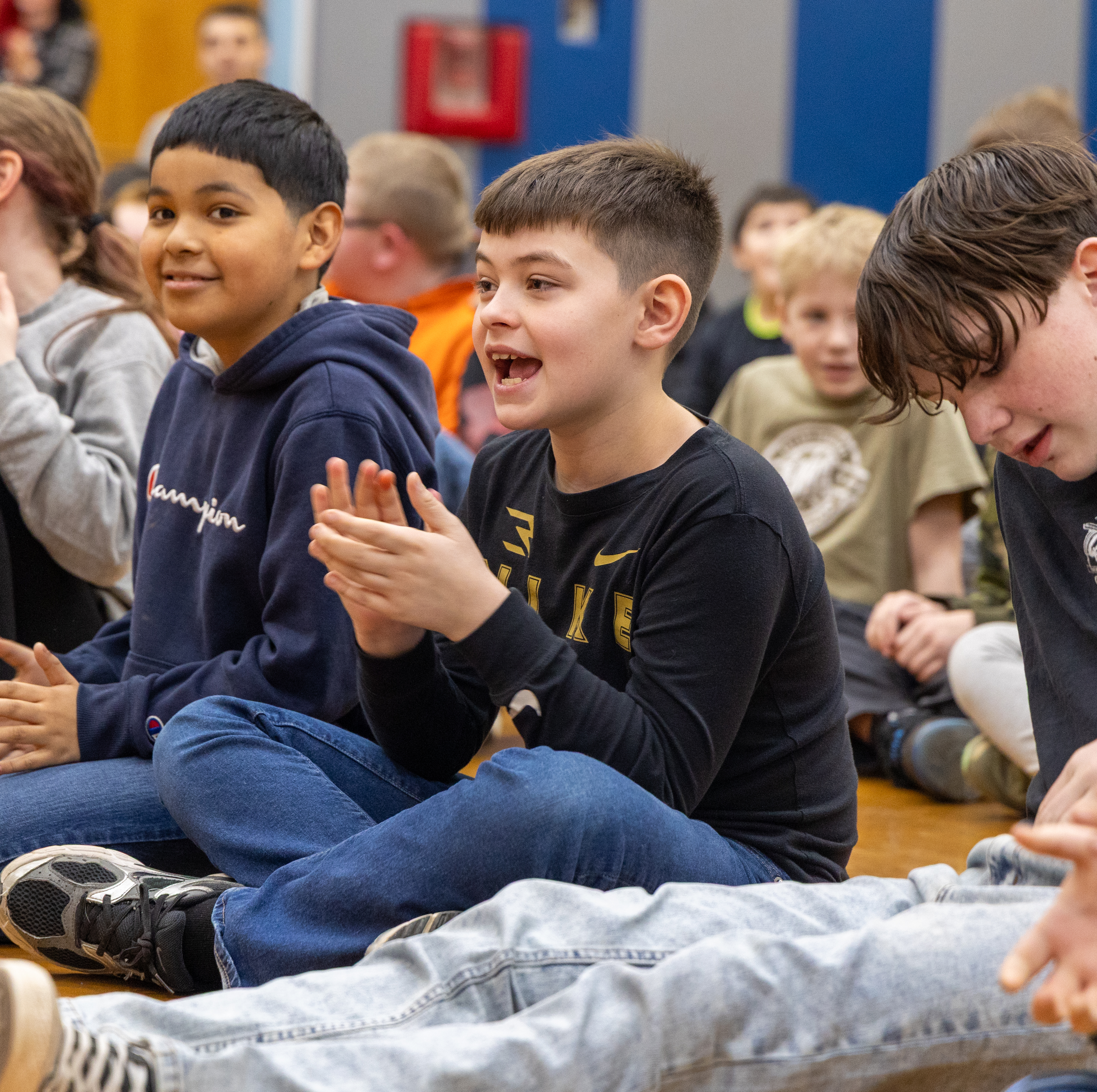 Students smiling and clapping while watching the show